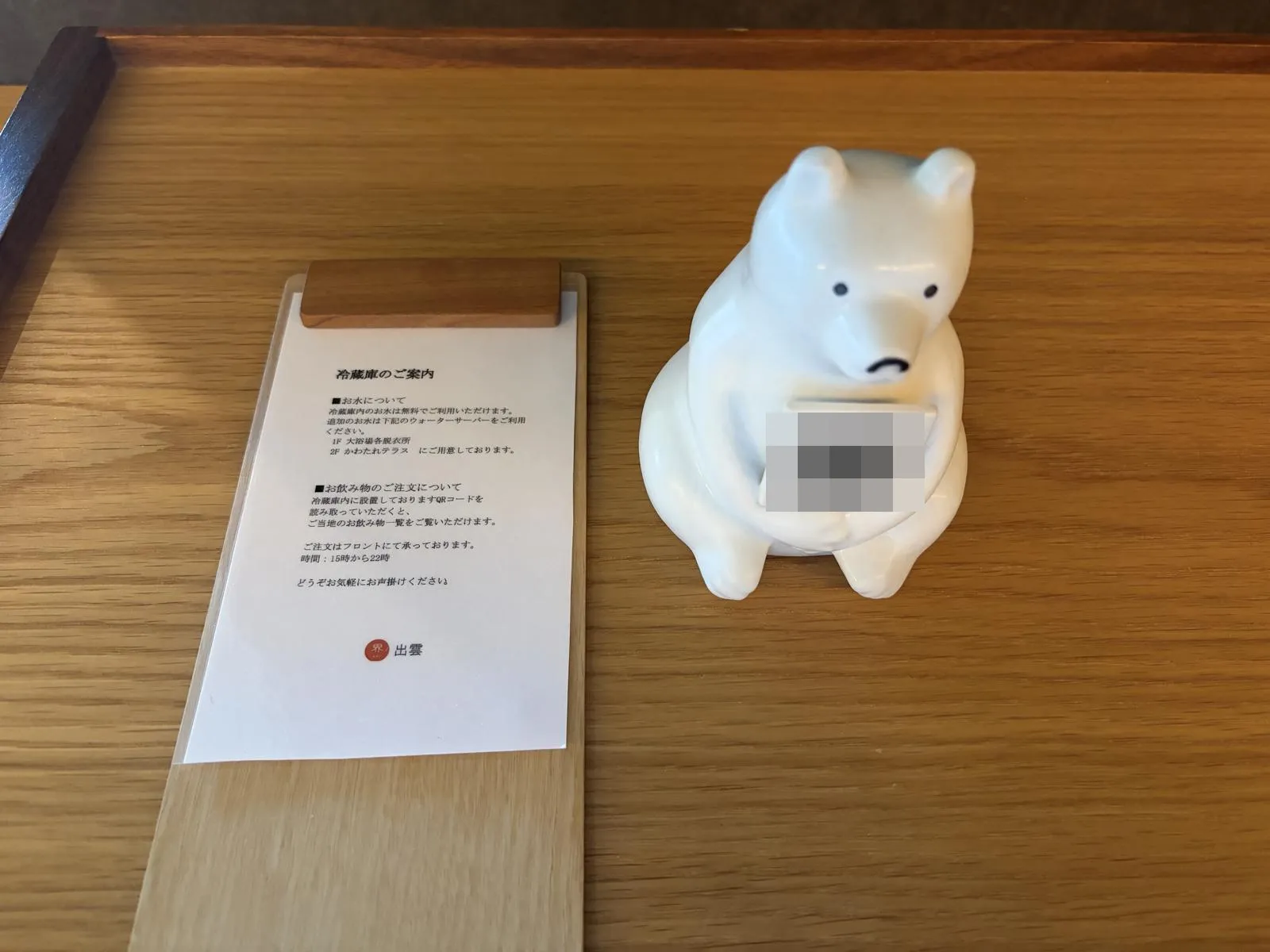 2次元バーコード（ぼかし加工済み）を抱えた白いクマの置物と、冷蔵庫の案内カード