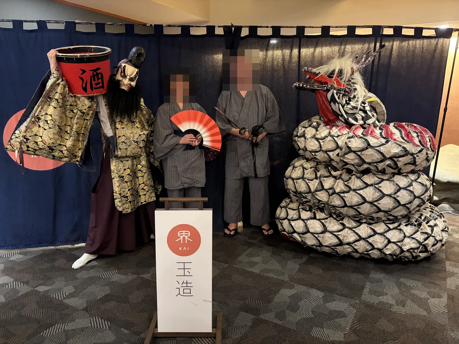 石見神楽の演者と大蛇の前で記念撮影する浴衣姿の夫婦
