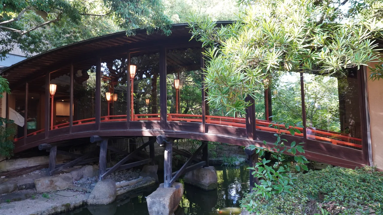 界 玉造の池にかかる朱色の太鼓橋と、緑に囲まれた庭園