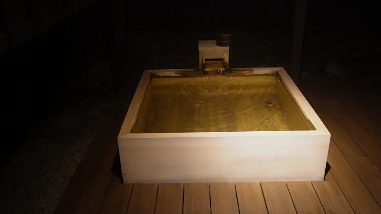 夜の明かりに照らされた檜の露天風呂