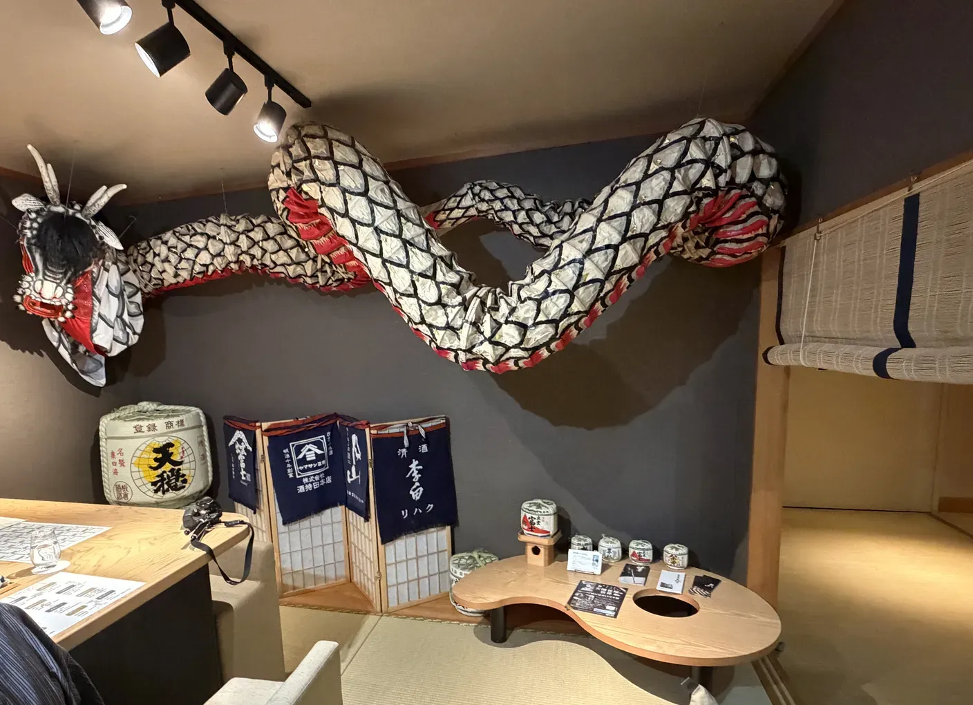 天井に大蛇の飾りが伸びる日本酒BARのカウンター