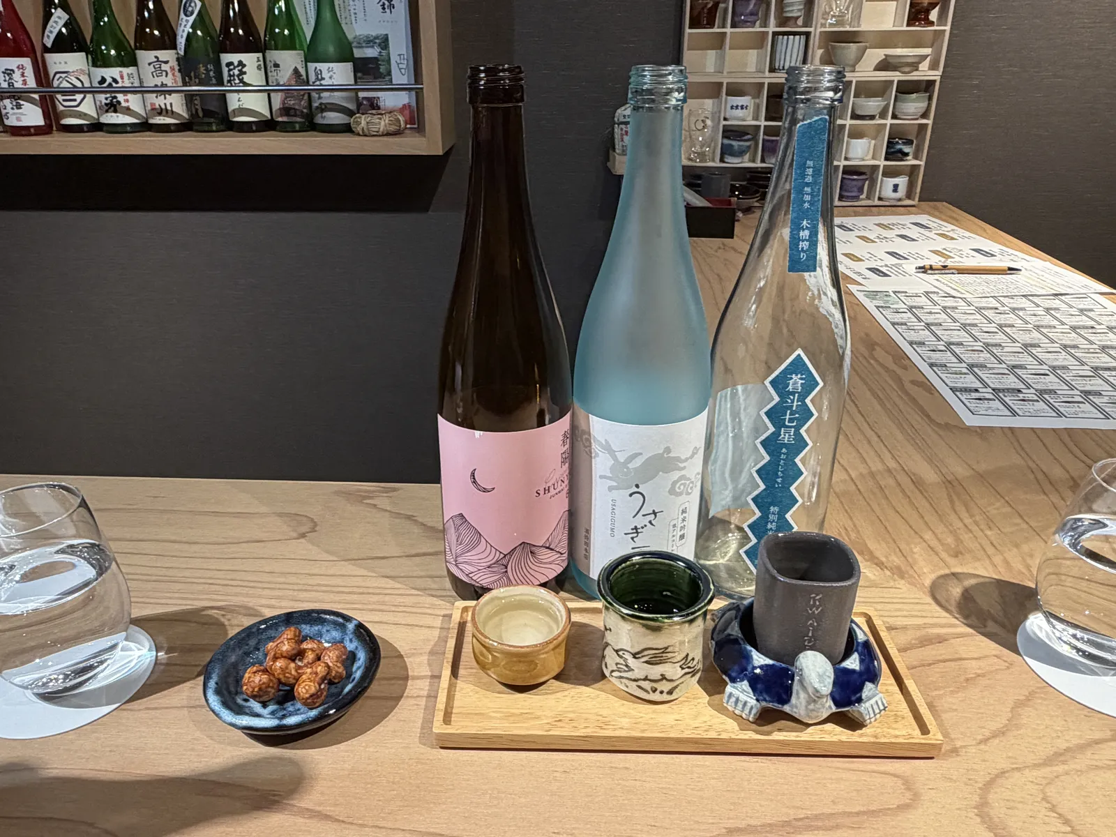 ピンク・水色・透明の3本の地酒と、飲み比べのおちょこ
