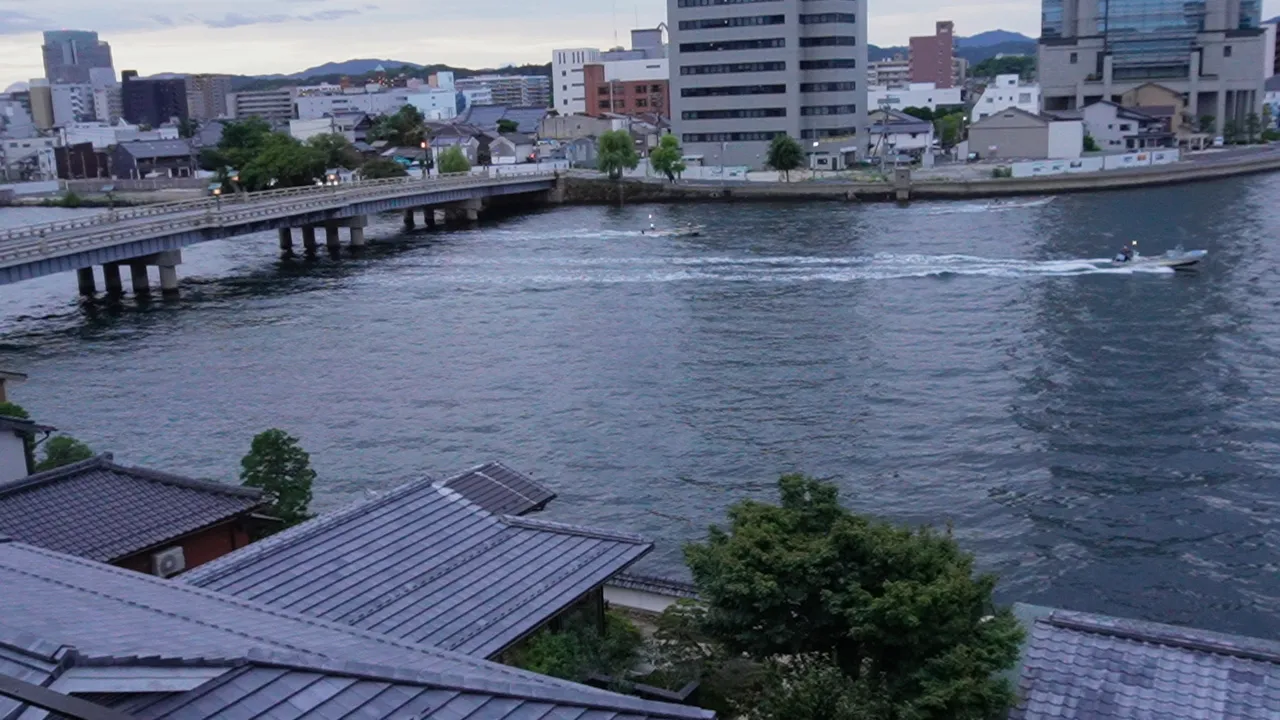 朝の宍道湖を進む小さな船と、松江の町並み