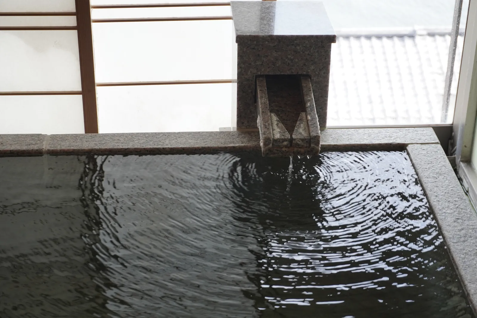 湯口から温泉が注がれる石の湯船