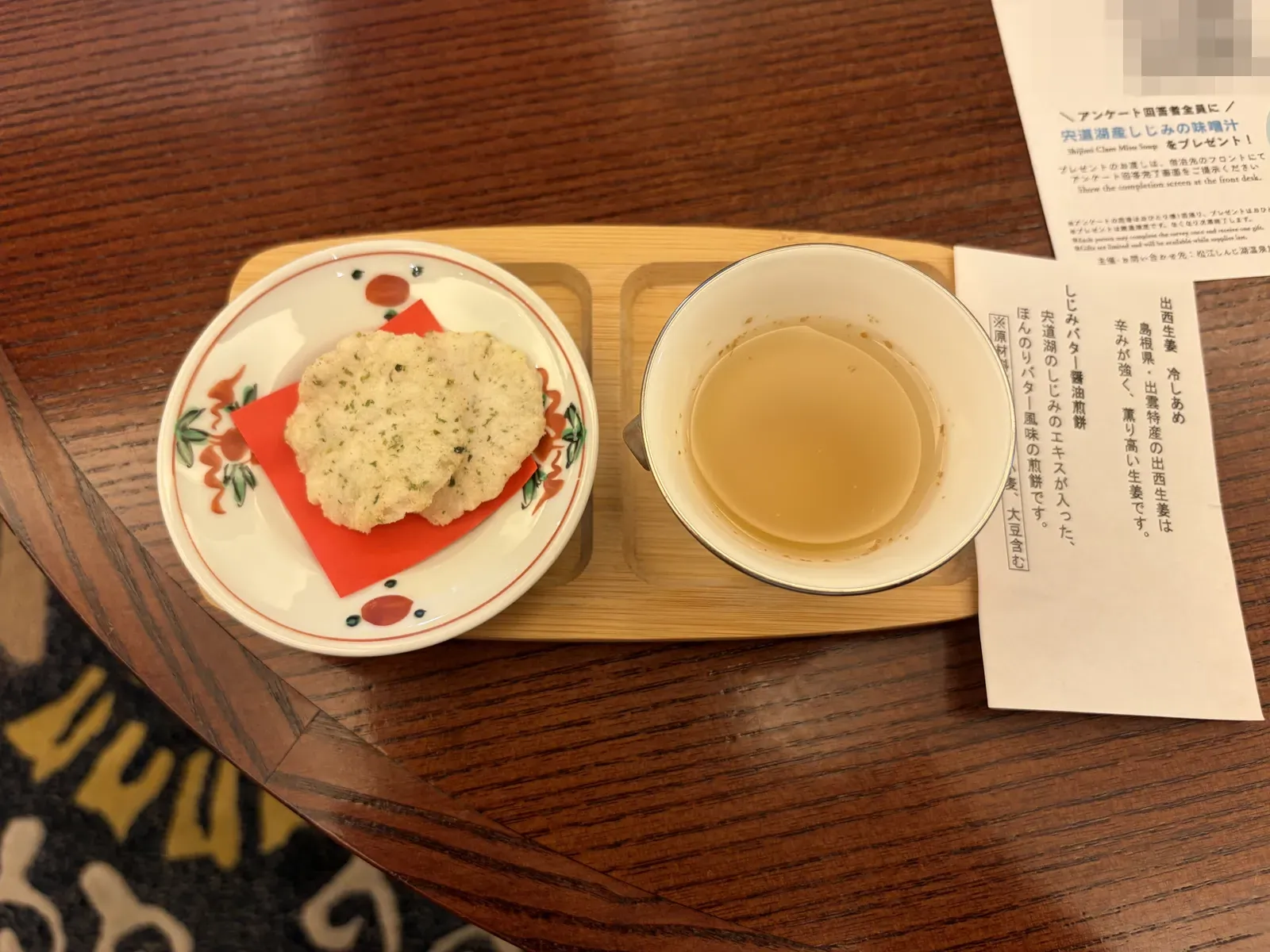 小皿にのったせんべいと、冷やしあめの器(カードの2次元バーコードはぼかし加工済み)