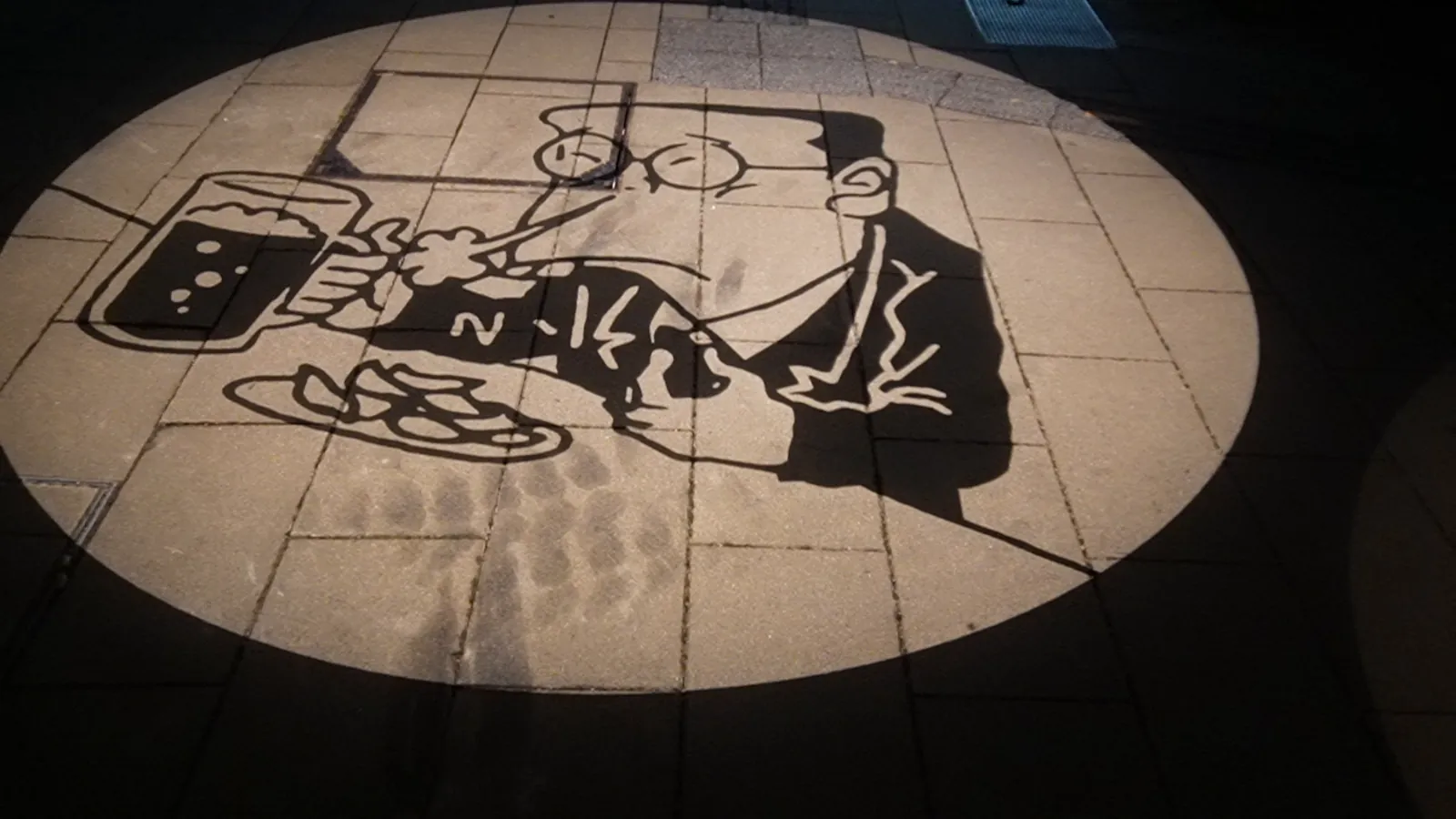 夜の路面に丸く映し出された影絵